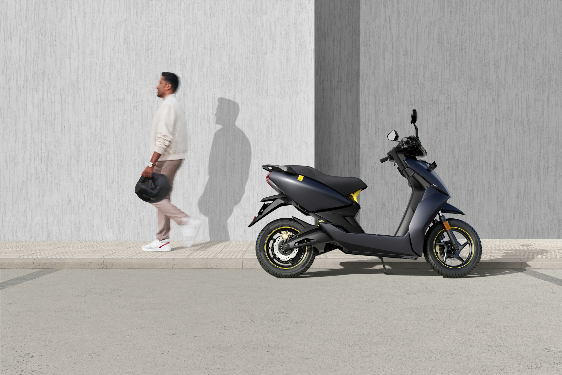Scooter elétrica moderna estacionada com homem ao fundo segurando um capacete.