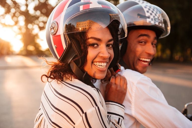 Homem e mulher sorrindo usando capacetes