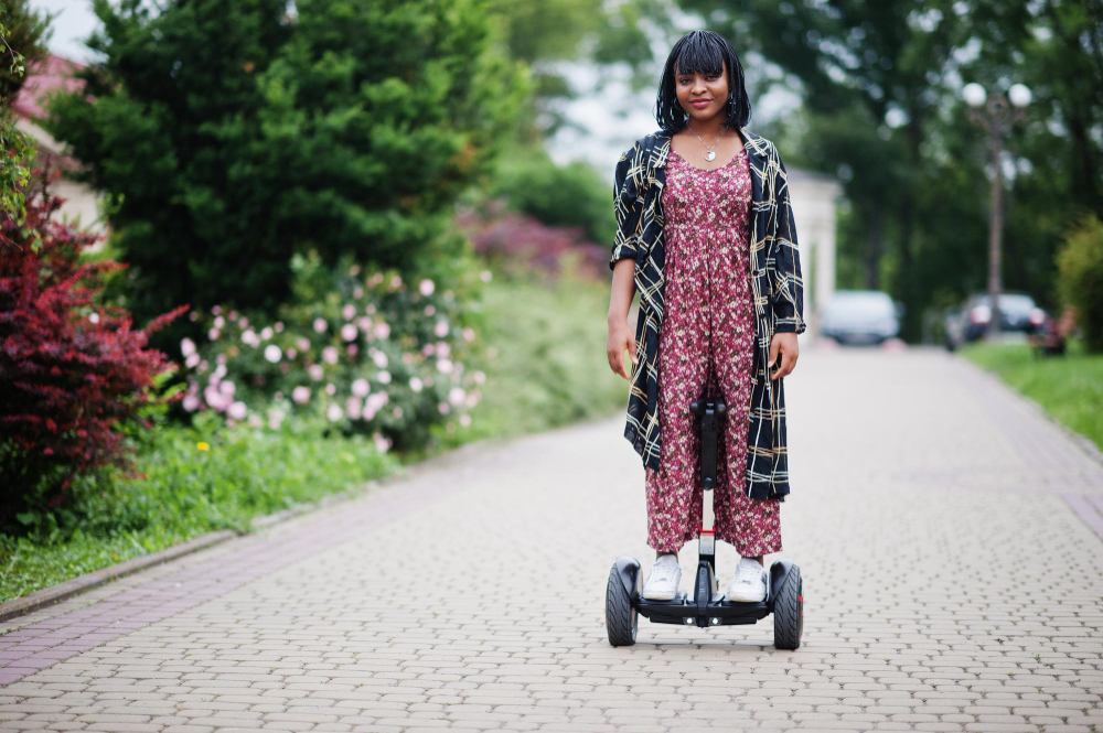 Mulher andando de hoverboard em rua arborizada – uso do hoverboard como transporte pessoal moderno e sustentável.