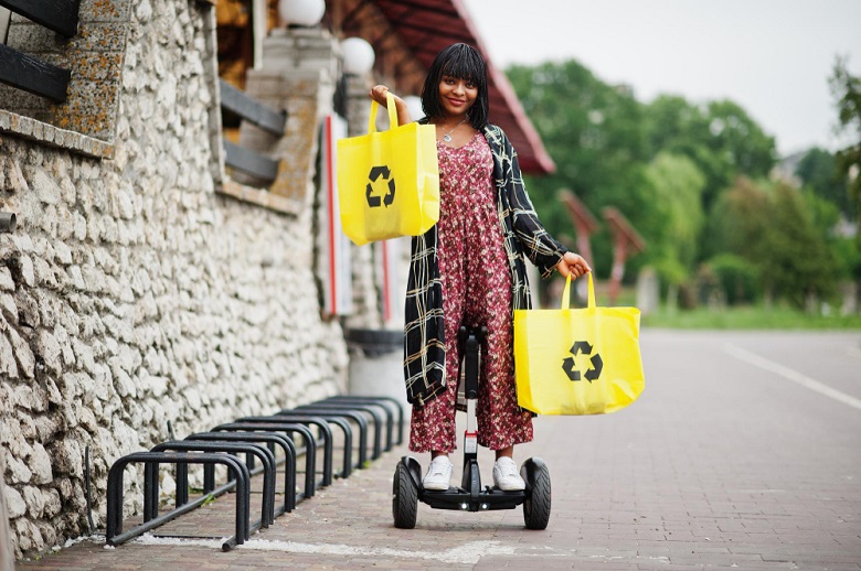 mulher segurando sacolas de compras em equipamento de mobilidade individual autopropelido