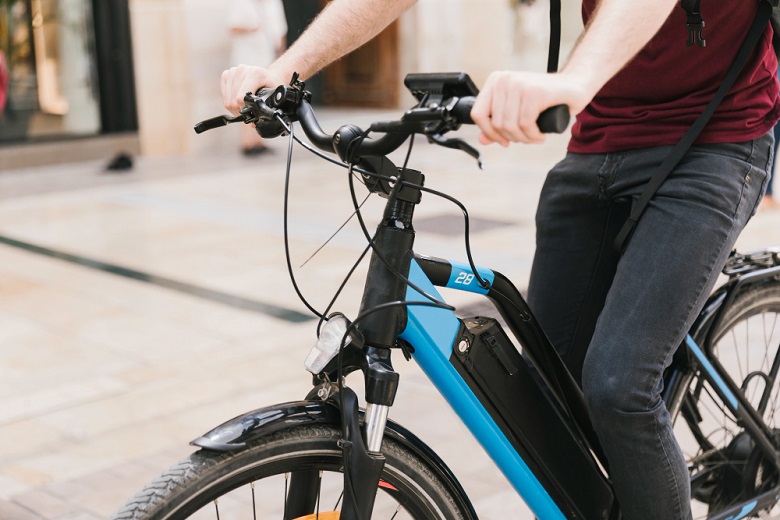 Ciclista em bicicleta elétrica circulando por área urbana com ciclovia e ciclofaixa próximas. 