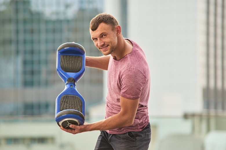 Homem segurando um hoverboard.