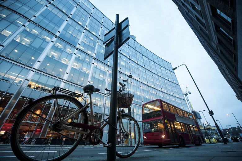 Bicycle and bus on road near modern building with glass facade