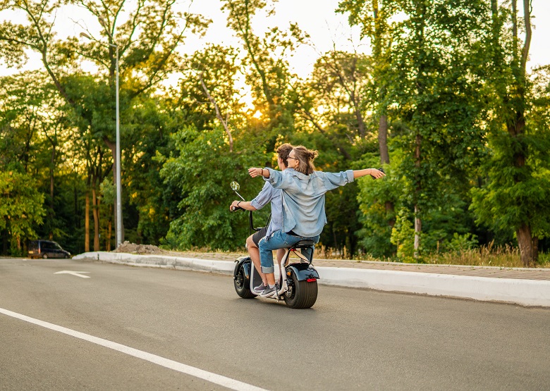 Lovely young couple driving electric bike during summer
